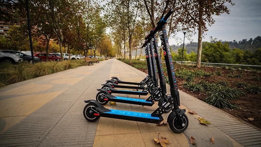 Muestra un grupo de scooters eléctricos en un área peatonal.